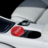 Lufterfrischer in Form eines Coca-Cola-Flaschenverschlusses auf einem Autositz.