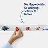 Magnetleiste mit bunten Figuren, die zur Ordnung dient, während eine Hand eine Figur anbringt.