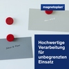 Rote Magneten halten beschriftete Kärtchen an einer glatten Oberfläche.
