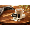 Zwei Kekspackungen in schwarz und weiß liegen auf einem Holztisch neben einer Tasse Kaffee.