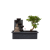 Bonsai-Wasserfall-Set mit Buddhafigur in einem grauen Behälter und einer grünen Bonsai-Pflanze.