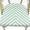 Stuhl mit grün-weißem, chevronförmigem Polyrattan-Sitz und goldfarbenem Gestell.