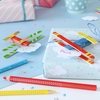 Buntstifte in Rot und Gelb liegen neben einem verzierten Geschenk mit einem Papierflugzeug.