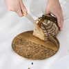 Schneidebrett aus Akazienholz mit gelasertem Schriftzug und Brot wird in der Hand geschnitten.