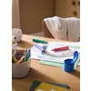 Dosenspitzer Grippy blau auf einem Tisch mit bunten Stiften und Papier.