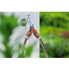 GARDENA 2-Wege-Verteiler mit zwei Schlauchanschlüssen am Wasserhahn in einer grünen Gartenumgebung.