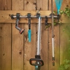 GARDENA Heckenschere EasyCut 55/18V hängt zusammen mit anderem Gartenzubehör an einer Holzwand.