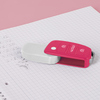 Weißer Radiergummi mit pinker Klappmechanik in Form eines Autoschlüssels auf einem Notizblock.