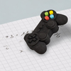 Radierer in Form eines Gamepads liegt auf kariertem Papier mit handschriftlichen Notizen.