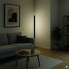 Minimalistische Stehleuchte in einem gemütlichen Wohnzimmer mit Sofa und Pflanze.