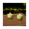 Zwei grüne, runde Solarleuchten mit warmem Licht auf einem Holztisch im Außenbereich.