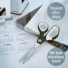 Schwarze Universalschere mit asymmetrischem Design, neben Kalender und Notizmaterial platziert.