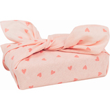 Rosa Stoffverpackung mit kleinen roten Herzen und einem Schleife oben drauf.