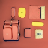 Coralfarbener Schulranzen mit gelben Accessoires auf einem einfarbigen Hintergrund.