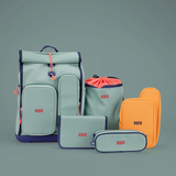 Schulranzen in Grau mit grünen und orangefarbigen Accessoires auf grauem Hintergrund.