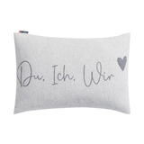 Grauer Kissenbezug mit dem Schriftzug "Du. Ich. Wir" und einem Herzen in der Ecke.