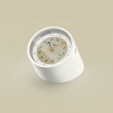 Wecker in Beige mit schlichtem Ziffernblatt und stabiler Grundform, auf einem hellen Hintergrund.