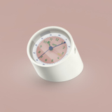 Wecker in dezentem Rosé mit grünen Ziffern und schlicher Designsprache auf hellem Hintergrund.