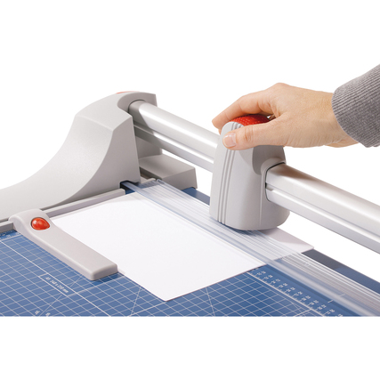 Hand, die einen Rollenschneider nutzt, um ein Blatt Papier auf einer Schneidemaschine zu schneiden.