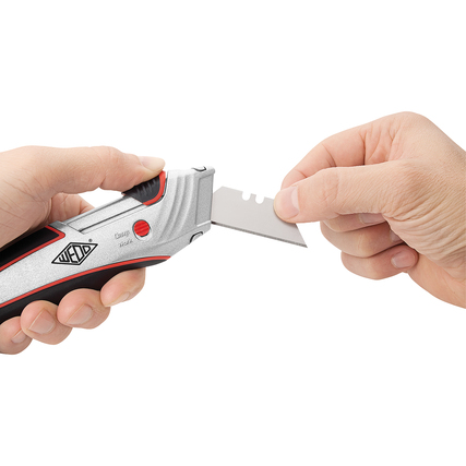 Person hält einen Cutter mit zurückziehbarer Klinge in der Hand, der zum Schneiden verwendet wird.