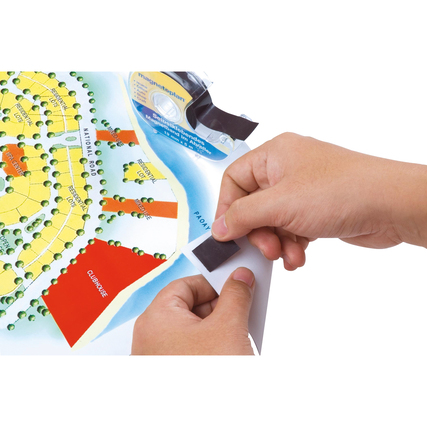 Hand, die ein Stück Magnetband von einem Handabroller abzieht, während ein Poster gehalten wird.