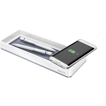 Graue und weiße Stiftschale mit zwei Stiften und einem aufladenden Smartphone im Vordergrund.