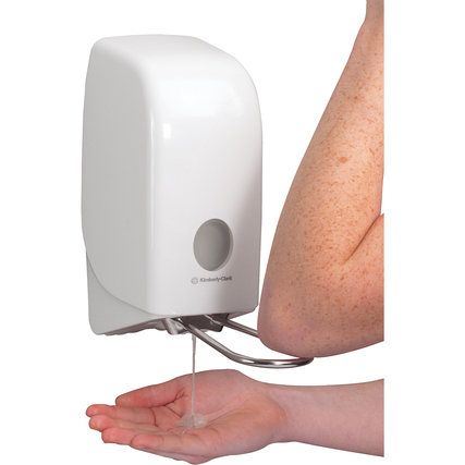 Weißer Wand-Seifenspender, der mit einem Armhebel bedient wird und Seife in eine Hand abgibt.