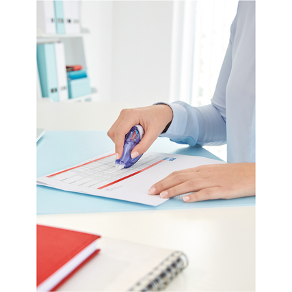 Hand einer Person, die einen Korrekturroller auf einem Blatt Papier verwendet.