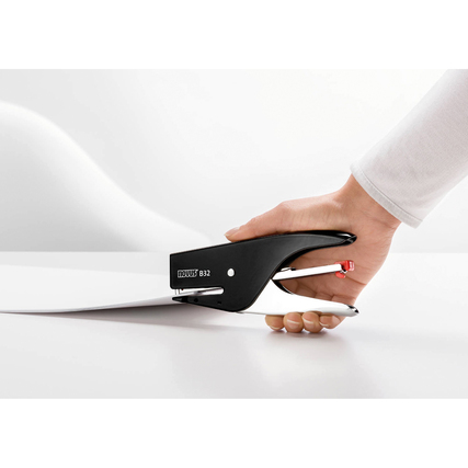 Heftzange in der Anwendung, gehalten von einer Hand, auf einem Stapel Papier.