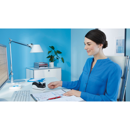 Tischabroller in Verwendung auf einem Schreibtisch mit blauem Hintergrund und Büroaccessoires.