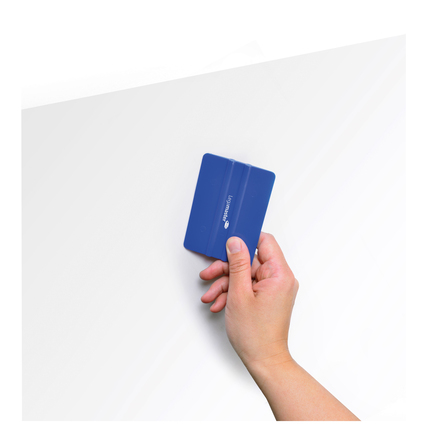 Hand hält blauen Rakel zur Anbringung von Whiteboardfolie auf glatter Oberfläche.
