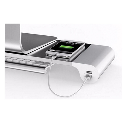 Monitorständer mit integriertem USB-Anschluss, auf dem ein Smartphone zum Laden liegt.