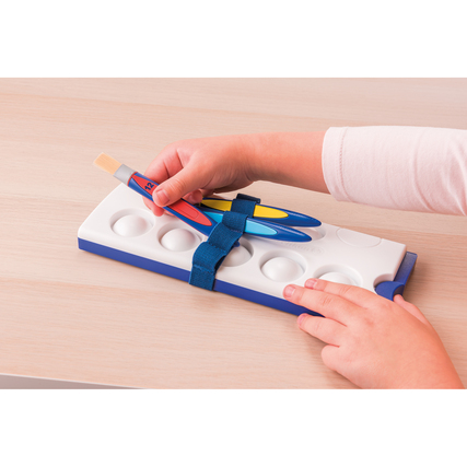 Hand eines Kindes mit Pinsel und Stiften auf einer Malkastenunterlage, die zum Aufbewahren dient.