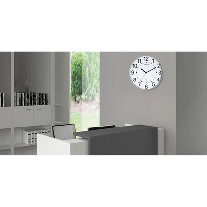 Funkuhr Maxi Wave in metallgrau an einer Wand in einem Büro mit modernen Möbeln.