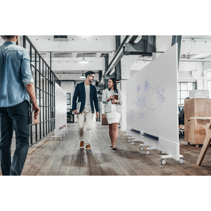 Zwei Personen gehen an einem mobilen, doppelseitigen Whiteboard mit Zeichnungen vorbei.