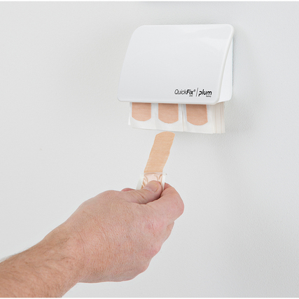 Weißer Pflasterspender an der Wand mit einer Hand, die ein desinfiziertes Pflaster entnimmt.
