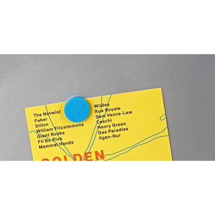 Blauer Magnet haftet an einer grauen Oberfläche und hält ein gelbes Papier mit Text.