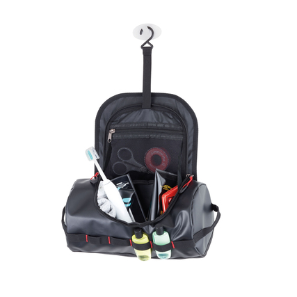 Schwarze Kulturbeuteltasche mit Inhalt, hängend an einem Haken, zwei Fächer sichtbar.