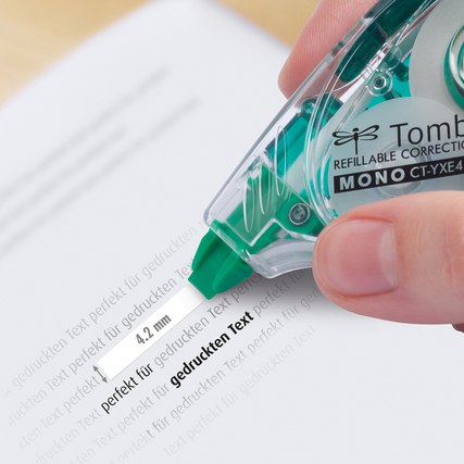Eine Hand hält einen Korrekturroller, der einen Text auf einem Blatt Papier überdeckt.