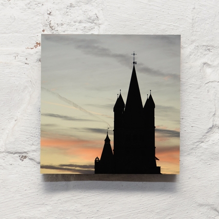 Dekobild mit Silhouette einer Kirche vor einem Sonnenuntergang auf weißer Wand.