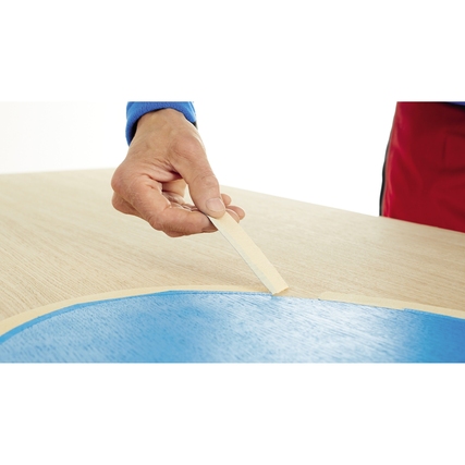 Hand hält ein Kreppband, das auf eine gewölbte Oberfläche geklebt wird.