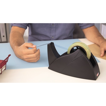 Schwarzer Tischabroller mit transparentem Klebeband auf einem Schreibtisch in Nutzung.