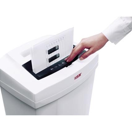 Person feedet Papier in einen weißen Aktenvernichter mit Bedienfeld.