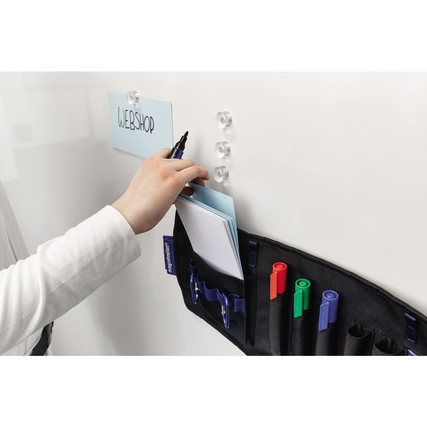Eine Hand platziert eine Notiz an einem Whiteboard neben einer moderierten Tasche mit Stiften.