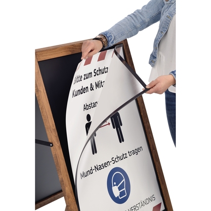 Person wechselt Plakat in einem doppelseitigen Kundenstopper mit Schutzinformationen.
