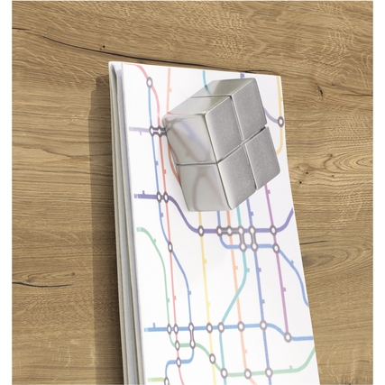 Glasboard mit geometrischem Design und Magneten an einer holzfarbenen Wand angebracht.