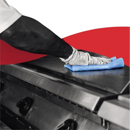 Hand mit grauem Handschuh, die ein blaues Wischtuch auf einer Grillplatte verwendet.