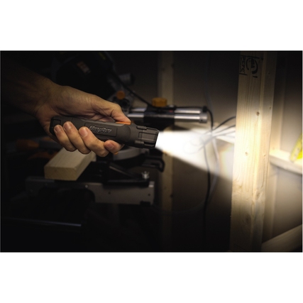 Energizer Taschenlampe in der Hand leuchtet auf Holz, umgeben von Werkstattutensilien.