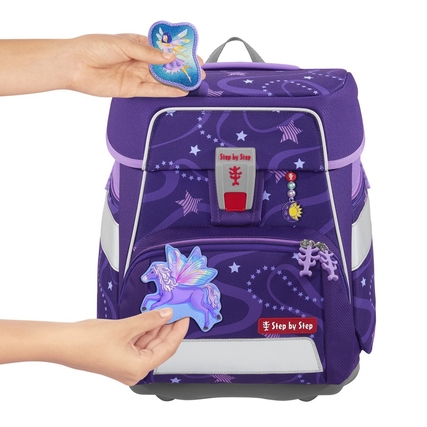 Magnetisches Accessoire in Form eines Pegasus wird an einem Schulranzen mit lila Design angebracht.