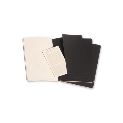 Drei schwarze Moleskine Cahier Notizhefte mit karierten und leeren Seiten sichtbar.